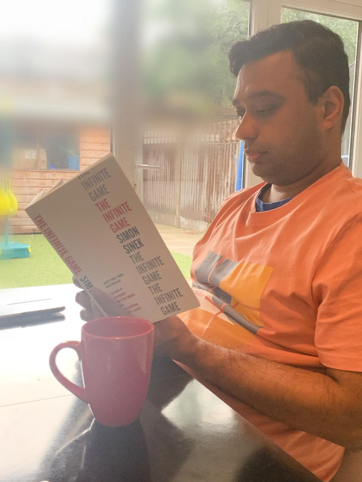 Srini reading The Infinite Game by Simon Sinek at home